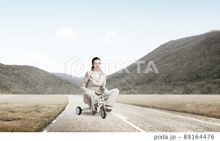 Caucasian woman riding kid's bicycle on road 89164476