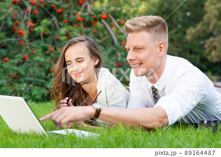businessman and businesswoman with a laptop in a city park 89164487