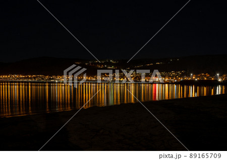 Town lights reflecting in a lake at night Town lights reflecting in a lake at night 89165709
