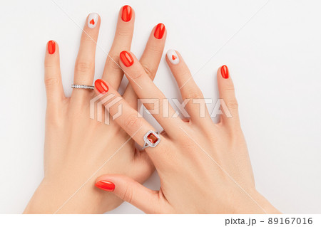 Womans hands with fashionable red manicure on white background. Summer nail design with heart Womans hands with fashionable red manicure on white background. Summer nail design with heart 89167016
