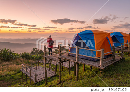 Woman photographer traveling and looking to beautiful view of the mountains range on Doi Sango (or Sa-Ngo) mountain in Chiang Saen district of Chiang Rai province of Thailand. Woman photographer traveling and looking to beautiful view of the mountains range on Doi Sango (or Sa-Ngo) mountain in Chiang Saen district of Chiang Rai province of Thailand. 89167106