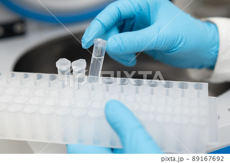 Female scientist in protective gloves picks up samples from the centrifuge and puts into the rack. Medicine and research concept. 89167692