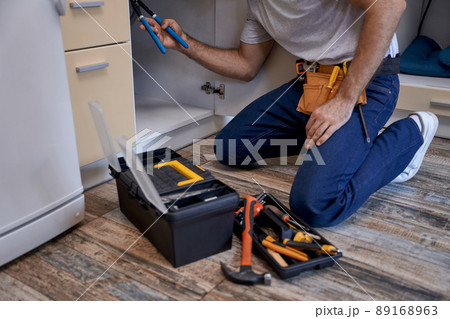 Young worker fixing tubes under kitchen sink 89168963