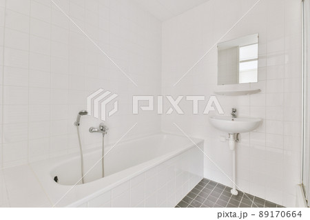 Bathroom with white and black tiles and ceramic bathtub and sink under the mirror in a modern house Bathroom with white and black tiles and ceramic bathtub and sink under the mirror in a modern house 89170664
