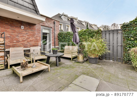 A spacious courtyard behind a residential building with a separate seating area on a tiled floor 89170777