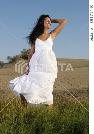 woman on the sand wearing white clothes under a blue sky woman on the sand wearing white clothes under a blue sky 89171440