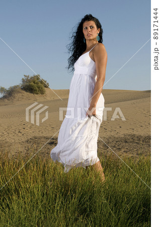 woman on the sand wearing white clothes under a blue sky woman on the sand wearing white clothes under a blue sky 89171444