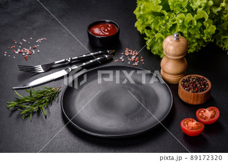 Empty round black plate on dark moody black background with copy space 89172320