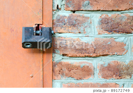 Padlock on metal door. Red brick wall 89172749