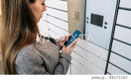 Post locker. Delivery automat terminal and hands with parcel courier box. Parcel delivery, pickup point with lockers, hand with parcel, contactless pack delivery. 89173162