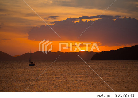 Beautiful orange sunset seascape view with boat and setting sun background Beautiful orange sunset seascape view with boat and setting sun background 89173541