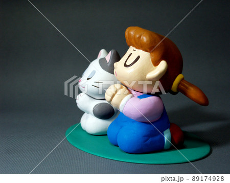 目を閉じ手を合わせ願い事をする女の子と猫 89174928