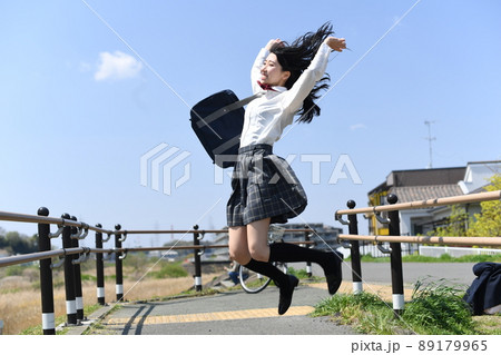 青空の下でジャンプをする笑顔の女子学生 青空の下でジャンプをする笑顔の女子学生 89179965