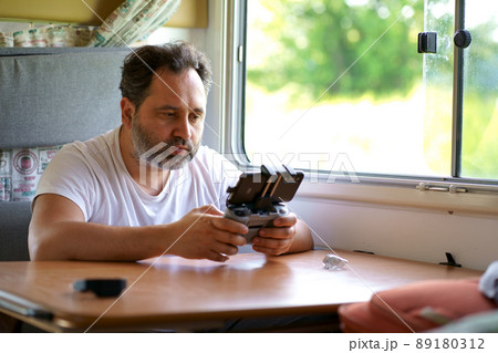 motorhome travel concept. Man controling a drone.a man controls a drone from the window of a motorhome 89180312