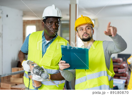 Two builders talking on indoor construction site Two builders talking on indoor construction site 89180870