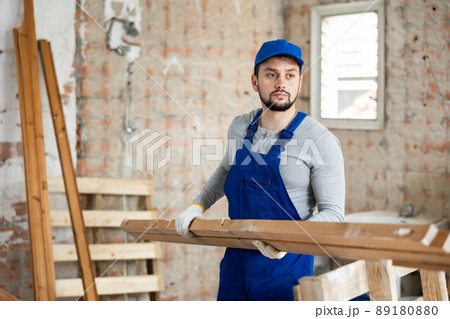 Professional builder holds wooden bars in his hands Professional builder holds wooden bars in his hands 89180880