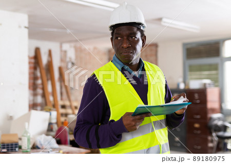 Strict building inspector standing with papers at construction site Strict building inspector standing with papers at construction site 89180975