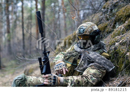 Concept of modern warfare - a mercenary soldier is resting after a clash in the forest. Concept of modern warfare - a mercenary soldier is resting after a clash in the forest. 89181215