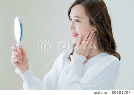 手鏡で肌荒れを確認する若い女性 手鏡で肌荒れを確認する若い女性 89181704