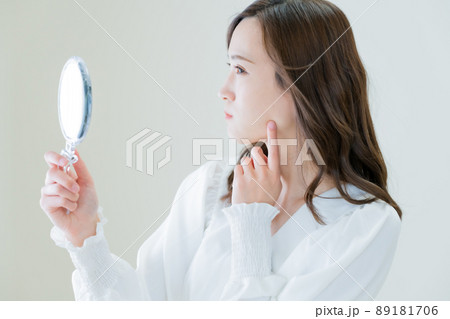 手鏡で肌荒れを確認する若い女性 89181706