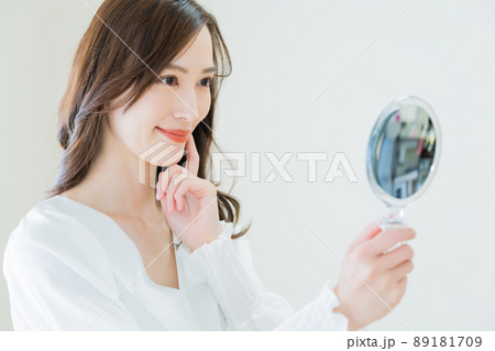 手鏡で肌荒れを確認する若い女性 89181709
