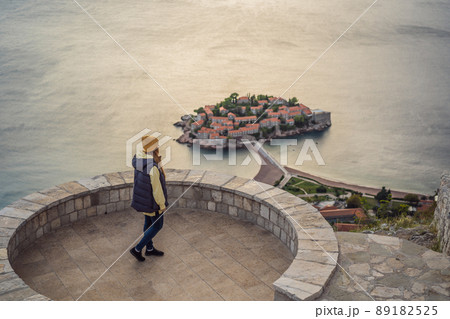 Woman tourist on background of beautiful view of the island of St. Stephen, Sveti Stefan on the Budva Riviera, Budva, Montenegro. Travel to Montenegro concept 89182525