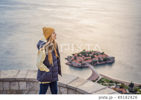 Woman tourist on background of beautiful view of the island of St. Stephen, Sveti Stefan on the Budva Riviera, Budva, Montenegro. Travel to Montenegro concept 89182826