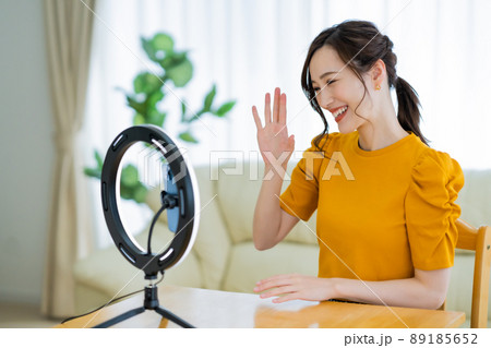 自宅で動画配信中にフォロワーに手を振る若い女性 89185652