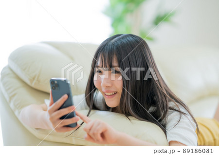 リビングのソファーでリラックスしながらスマホを見る高校生 リビングのソファーでリラックスしながらスマホを見る高校生 89186081