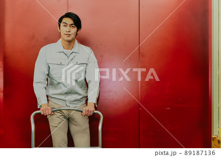 貨物用エレベーターの前で台車を押す男性 89187136