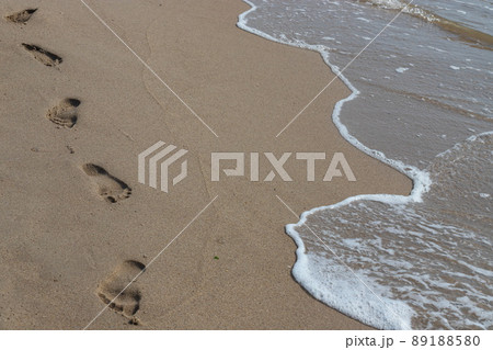 Footprints in the sand beach. Footprints in the sand against a sea wave. Footprints on a sunny day with golden sand, beach, wave and footsteps 89188580