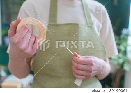 Decorative ribbon of beige color in the hands of a florist, close-up 89190061