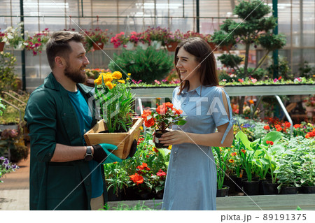Worker helping female customer with plant in garden center 89191375