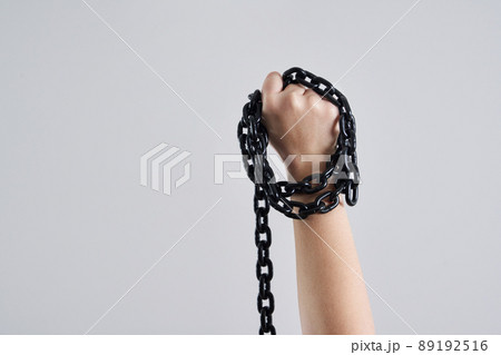 Female fist holding metal chain high up over grey background 89192516