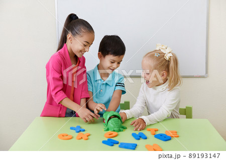 Preschool children playing with alphabet letters on a desk 89193147