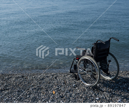 An empty wheelchair on a rocky seashore. An empty wheelchair on a rocky seashore. 89197847