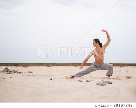 Caucasian man with long hair practicing qigong outdoors. Caucasian man with long hair practicing qigong outdoors. 89197848