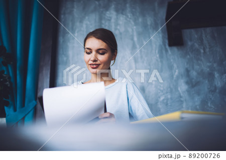Concentrated woman with sheet of paper in room Concentrated woman with sheet of paper in room 89200726