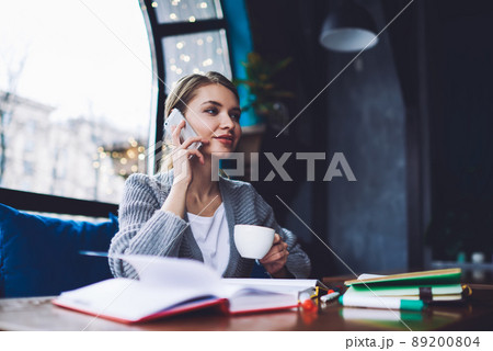 Dreamy woman having conversation on smartphone Dreamy woman having conversation on smartphone 89200804