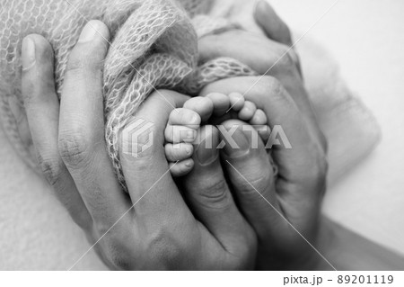 Mother is doing massage on her baby foot. Closeup baby feet in mother hands. Prevention of flat feet, development, muscle tone, dysplasia. Family, love, care, and health concepts. Studio macro. 89201119