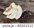 Sweet ripe melon cut on a wooden table with spilling seeds. 89201512
