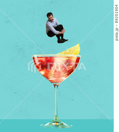 Contemporary art collage. Happy cheerful man jumping into refreshing tasty cocktail with fruity taste isolated over blue background Contemporary art collage. Happy cheerful man jumping into refreshing tasty cocktail with fruity taste isolated over blue background 89201904