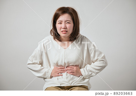 お腹が痛くて手でおさえる若い女性 89203663