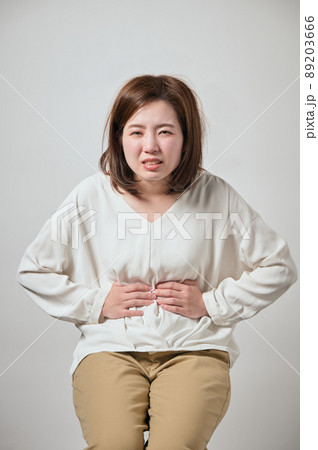 お腹が痛くて手でおさえる若い女性 89203666