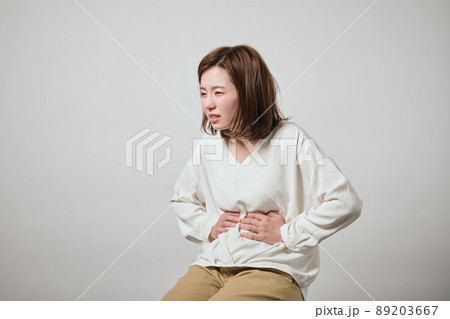 お腹が痛くて手でおさえる若い女性 89203667