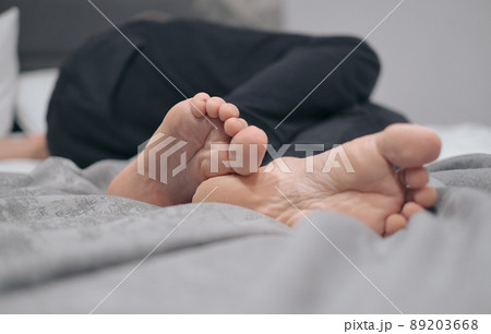 Close-up of male legs with feet forward lying on the bed while resting. Vacation concept Close-up of male legs with feet forward lying on the bed while resting. Vacation concept 89203668