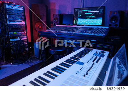 Horizontal no people shot of recording studio room interior with mixing console, digital piano, loudspeakers and other equipment in neon light Horizontal no people shot of recording studio room interior with mixing console, digital piano, loudspeakers and other equipment in neon light 89204979