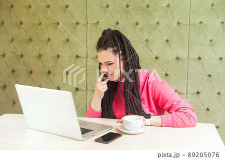 You are liar. Young freelancer woman with black dreadlocks hairstyle in pink blouse is sitting and making video call on laptop, talking and pointing finger to nose to showinn lie gesture. indoor You are liar. Young freelancer woman with black dreadlocks hairstyle in pink blouse is sitting and making video call on laptop, talking and pointing finger to nose to showinn lie gesture. indoor 89205076