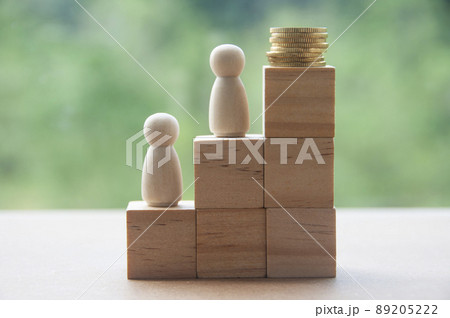 Wooden dolls standing on stack of wooden blocks with gold coins on top. Business concept 89205222