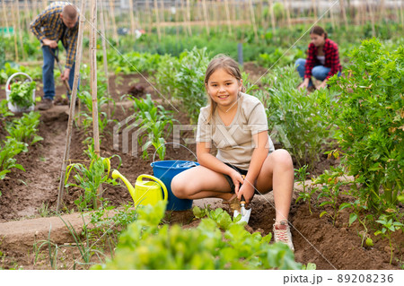 Positive girl with chopper removes weeds from garden beds Positive girl with chopper removes weeds from garden beds 89208236